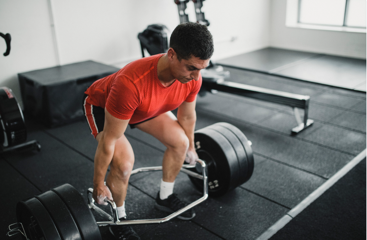 Man deadlifts with a hex bar in a gym